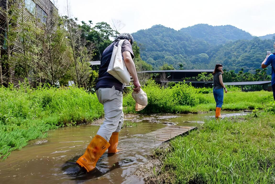 一行人穿著雨鞋踏過木板。