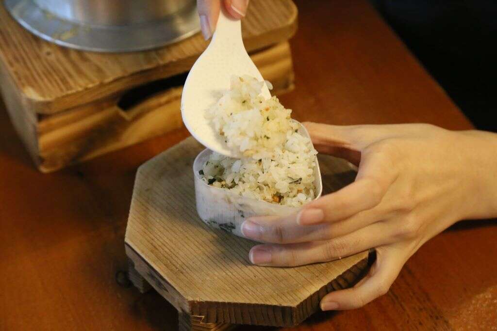 將魩仔魚香鬆拌入飯中，再放到三角飯糰的模型內壓緊至成形